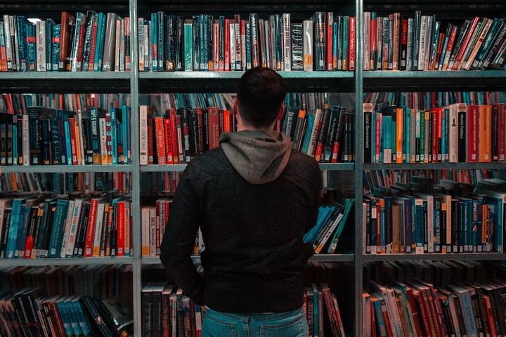 Persona frente a las estanterías de una biblioteca